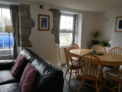 a living room with a table and a leather couch at Fishermans Cottage in Portland