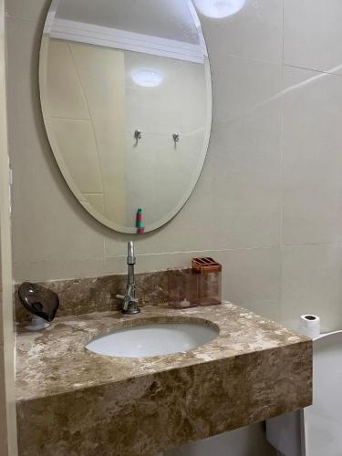 a bathroom with a sink and a mirror at Flat Ilhéus - Jubiabá Olivença in Ilhéus