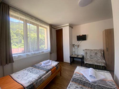 a bedroom with two beds and a window and a chair at Анелия in Sapareva Banya