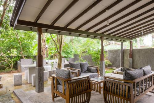 a wooden pergola with chairs and tables on a patio at Dollyz Home - Sri Lanka in Ambalangoda