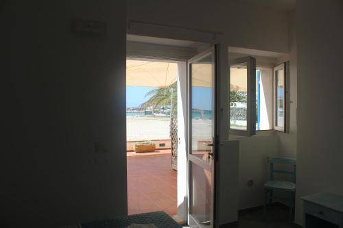 a view of the beach from a room with an open door at Vel Marì - Rooms on the Beach in Alghero