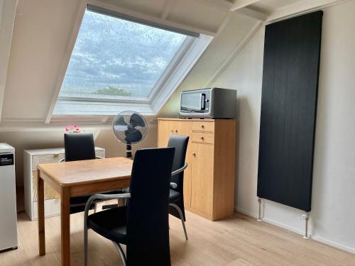 a dining room with a table and a window at Zolderstudio dichtbij Goffert met eigen badkamer en WC, eigen keuken, eigen ingang in Nijmegen