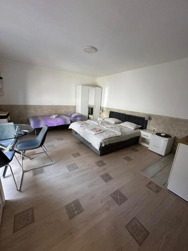 a bedroom with two beds and a table and a desk at Relax apartmani in Kragujevac