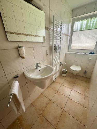 a white bathroom with a sink and a toilet at Nierswalder Landhaus in Goch