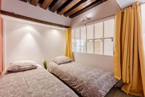 deux lits dans une chambre avec une fenêtre dans l'établissement Loft lumineux authentique, à Paris