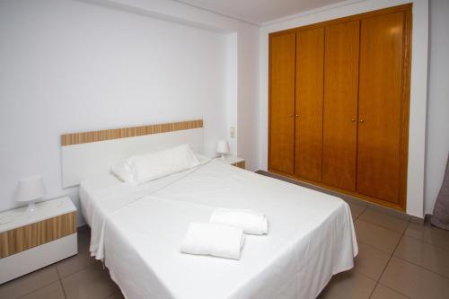 a bedroom with a white bed with two towels on it at Patacona deluxe primera linea in Valencia