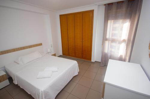 sypialnia z białym łóżkiem i drewnianą szafką w obiekcie Patacona deluxe primera linea w Walencji