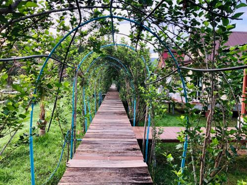 a wooden boardwalk through a garden with an arbor at Baan Thung Home Stay in Prasat