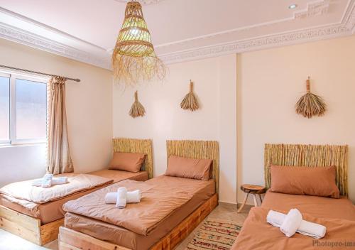 een kamer met 2 bedden en een bank bij Surf Bliss tamraght in Tamraght Ouzdar