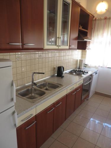uma cozinha com armários de madeira, um lavatório e um frigorífico em Apartments Gloria em Biograd na Moru