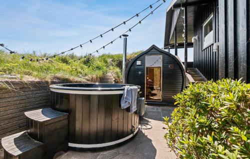 Una pequeña casa negra con una bañera delante. en 3 Bedroom Stunning Home In Løkken, en Løkken