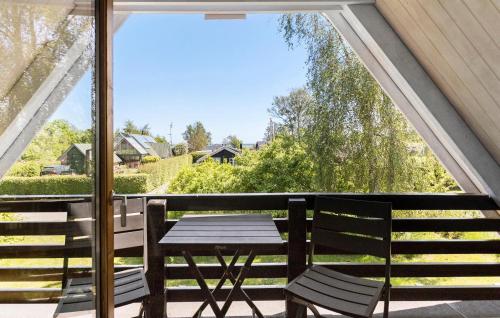 斯波斯比约Beautiful Home In Rudkøbing With Wifi的阳台设有一张桌子和两把椅子,并设有一个窗户