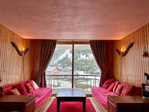 Elle comprend un salon doté d'un mobilier rose et d'une grande fenêtre. dans l'établissement Appartement Front de neige, à Isola