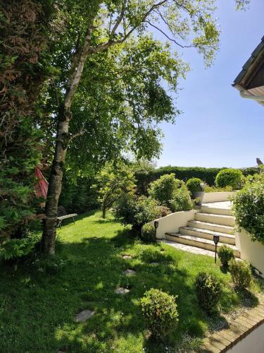 un jardin avec des escaliers, de la pelouse verdoyante et des arbres dans l'établissement Chambre d'hôte proche d'Étretat, à Saint-Jouin-Bruneval
