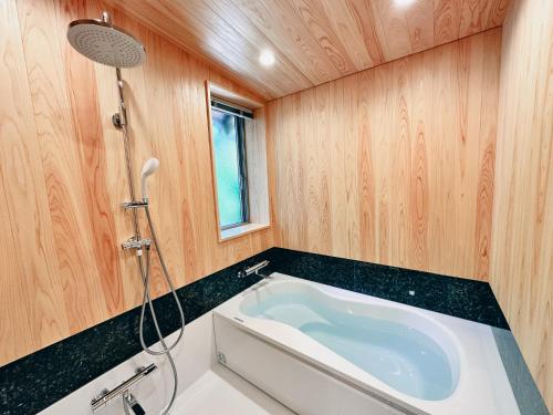 a bath tub in a bathroom with wooden walls at 閑雲庵 -Kan un an- in Ayagawa