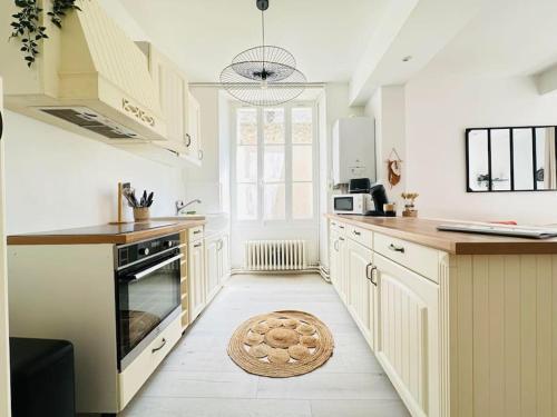 a kitchen with white cabinets and a rug on the floor at Appartement la Citadelle in Laon