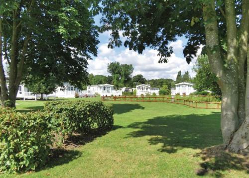 un parc avec une clôture, des arbres et des maisons dans l'établissement Fir Trees, à Chester