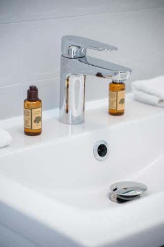 - un lavabo dans la salle de bains avec 2 bouteilles d'huiles essentielles dans l'établissement Le COQ Eden - Air conditioning - Seafront, à Roquebrune-Cap-Martin