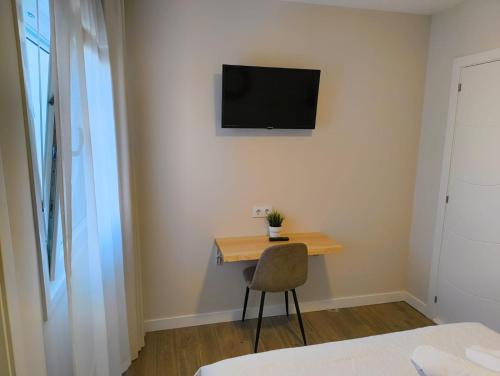 a small desk with a chair and a television on a wall at Villa Galicia (Padrón) in Padrón