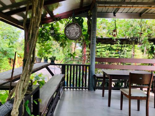 een veranda met tafels en stoelen en een bord bij Baan Thung Home Stay in Prasat