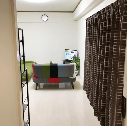 a living room with a couch and a clock on the wall at Rosemary 201 in Kagoshima