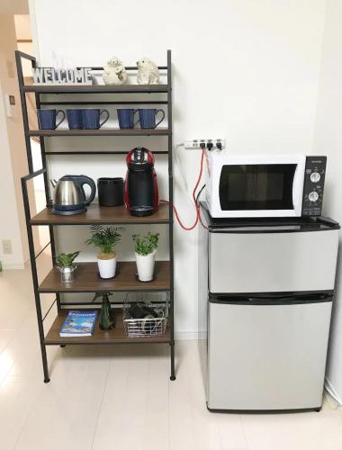 una cucina con un microonde e uno scaffale con pentole e padelle di Rosemary 201 a Kagoshima