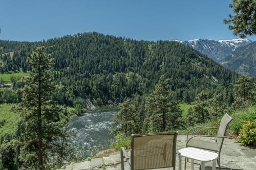 a table and chair sitting on a rock ledge overlooking a river at River Heights Home cabin in Leavenworth