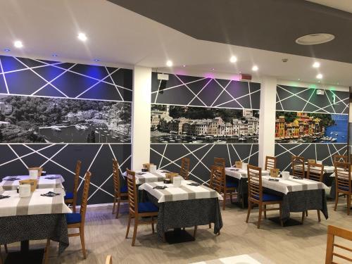 een restaurant met tafels en stoelen en een grote muurschildering bij Hotel Portofino in Caorle