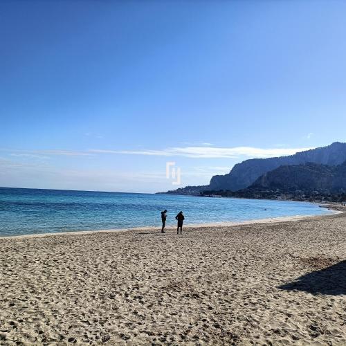 two people standing on a beach next to the ocean at La casetta della Letizia in Mondello