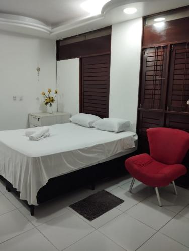 um quarto com uma cama e uma cadeira vermelha em La Playa Hospedagem em João Pessoa