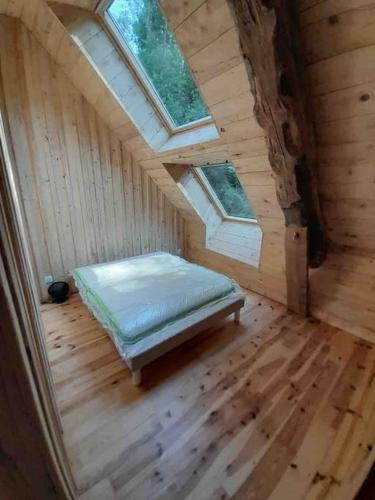Cette chambre comprend un lit dans une chambre en bois dotée de fenêtres. dans l'établissement La Grange de la Gratade, à Rochefort-Montagne