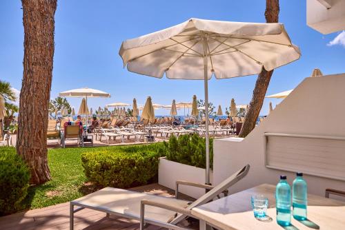 a patio with an umbrella and tables and chairs at Aparthotel Ponent Mar in Palmanova