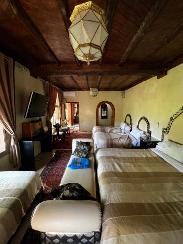 a room with four beds and a tv and a couch at Jnane Ayam Atlas in Ourika