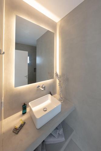 a bathroom with a white sink and a mirror at Ventus Villas in Mikonos