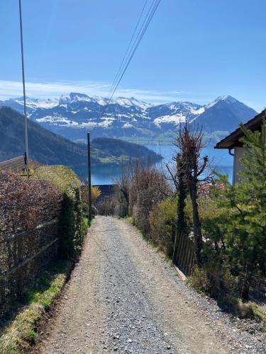 een onverharde weg met besneeuwde bergen in de verte bij Cozy House above Lake Lucerne in car-free Vitznau Mittlerschwanden at Mount Rigi railway in Vitznau