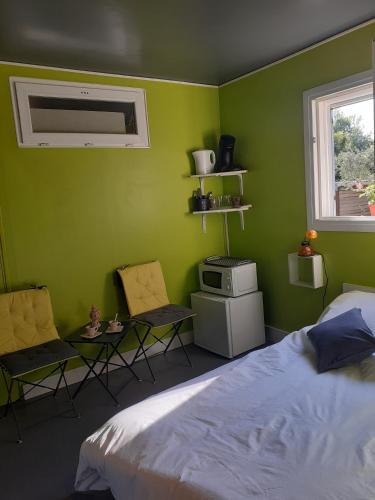 - une chambre avec des murs verts, un lit et des chaises dans l'établissement Location saisonnière avec piscine et terrasse au pied du luberon, à Lauris