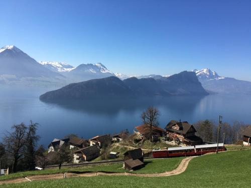 pociąg przejeżdżający obok wioski na wzgórzu z górami w obiekcie Cozy House above Lake Lucerne in car-free Vitznau Mittlerschwanden at Mount Rigi railway w mieście Vitznau