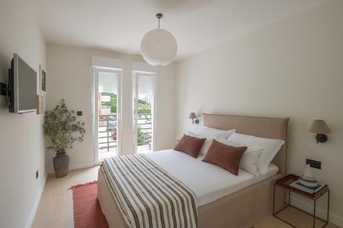 a bedroom with a bed with white sheets and a window at Design Coastal Garden Apartment in Split