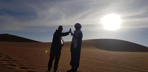 two people standing in the sand in the desert at Desert Waves Excursion in Mhamid