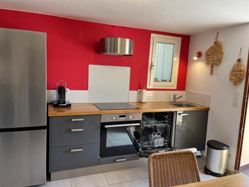 - une cuisine avec des murs rouges et un comptoir dans l'établissement Appartement deux pièces donnant sur un jardin, à Antibes