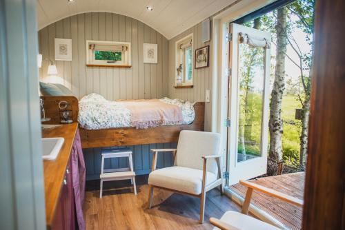 a bedroom with a bed and a desk and a chair at Tiny Houses Bij De Compagnons in Waskemeer