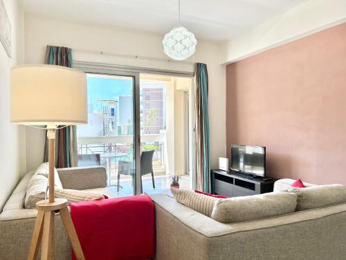 a living room with a couch and a television at SUN JULZ Apartments on the Beach in Paphos