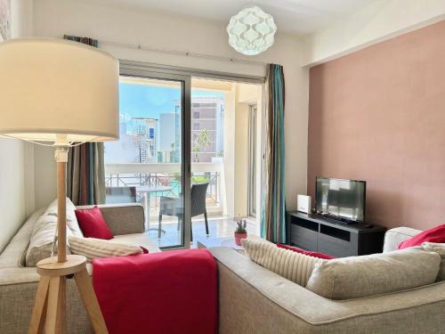 a living room with a couch and a television at SUN JULZ Apartments on the Beach in Paphos
