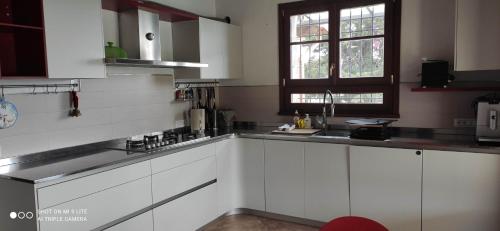 a white kitchen with white cabinets and a window at Cintoia, Tuscany Beautiful villa with private pool in Santa Luce