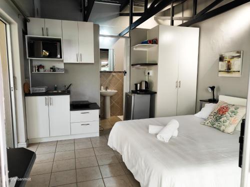 a bedroom with white cabinets and a white bed at D'urbanmist in Durbanville