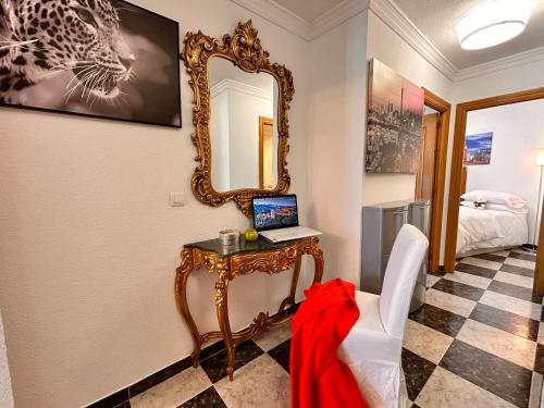 Habitación con espejo y mesa con ordenador portátil en Íberos Royal en La Zubia