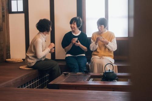 three women sitting on stairs looking at their cell phones at 閑雲庵 -Kan un an- in Ayagawa
