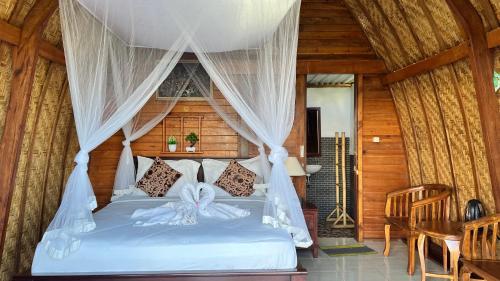 a bedroom with a white bed with a canopy at Pondok Valen mountain view in Kubupenlokan