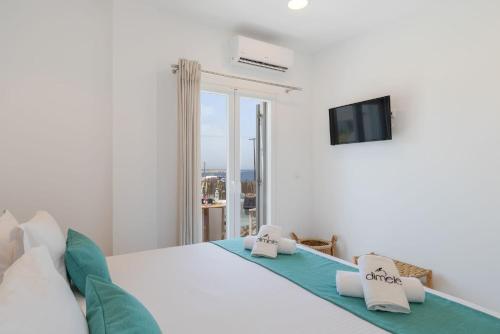 a white bedroom with a bed and a window at Dimele in Mikonos