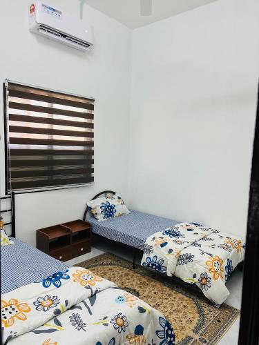a room with two beds and a window at De Bunga Homestay in Parit Raja
